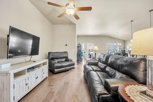 living area featuring vaulted ceiling, light wood-style flooring, and ceiling fan with notable chandelier