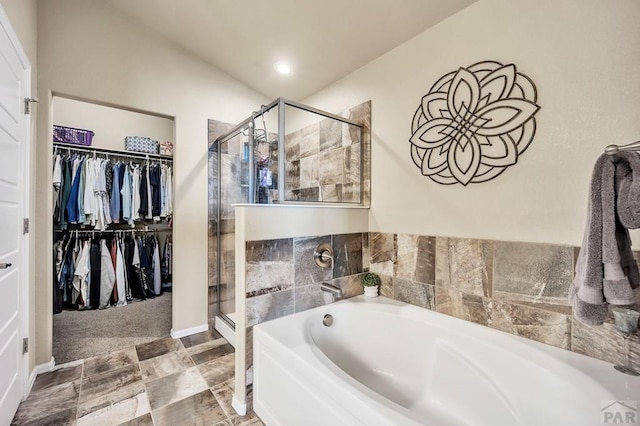 full bath with a stall shower, a spacious closet, and a bath