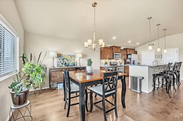 dining room featuring lofted ceiling, an inviting chandelier, light wood-style flooring, and baseboards