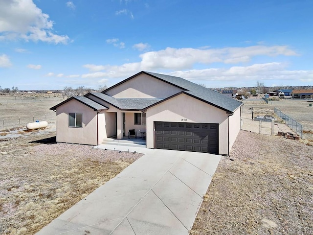 view of front of home with stucco siding, a shingled roof, concrete driveway, fence, and a garage