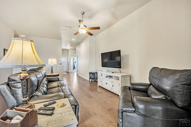 living room with ceiling fan, wood finished floors, visible vents, and baseboards