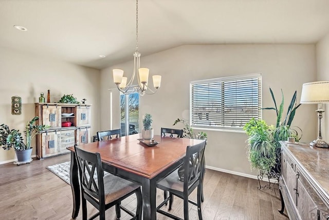 dining area featuring lofted ceiling, light wood-type flooring, baseboards, and an inviting chandelier