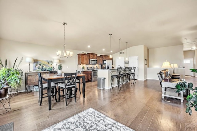 dining space featuring light wood finished floors, baseboards, vaulted ceiling, and an inviting chandelier