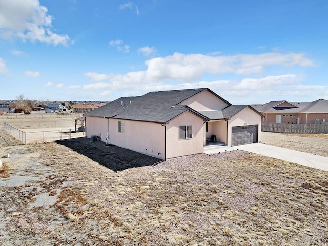 view of front of house featuring an attached garage, fence, concrete driveway, and stucco siding