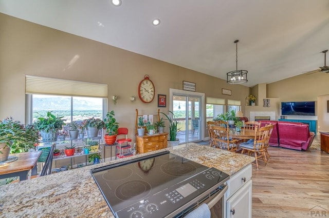 kitchen with hanging light fixtures, a wealth of natural light, white cabinetry, and electric stove