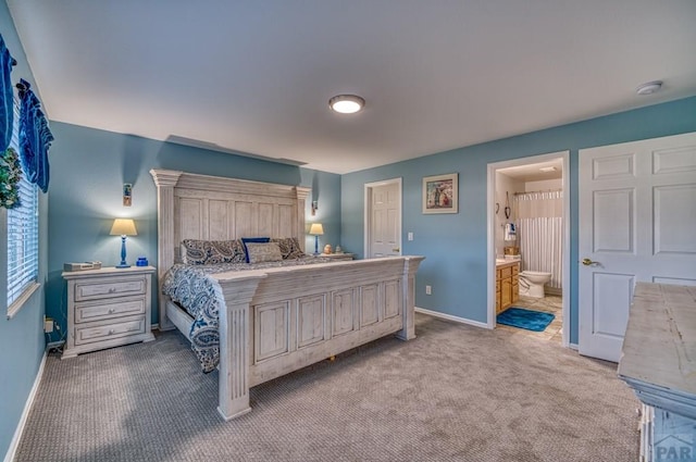 bedroom featuring baseboards, ensuite bath, and light colored carpet