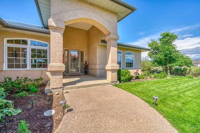 property entrance featuring a lawn and stucco siding