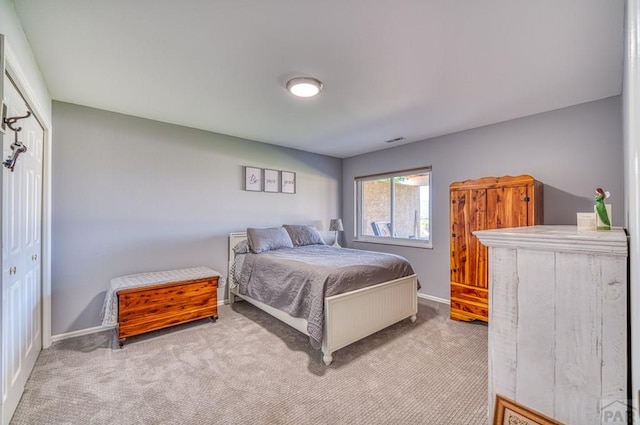 bedroom with a closet, light carpet, visible vents, and baseboards