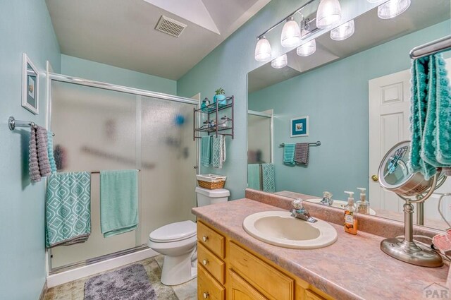 bathroom with a stall shower, visible vents, vanity, and toilet