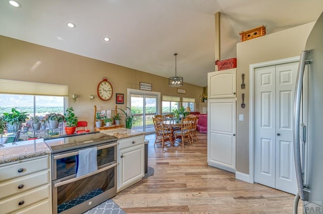 kitchen featuring appliances with stainless steel finishes, light stone countertops, white cabinets, and pendant lighting