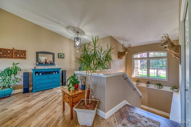 interior space with baseboards, lofted ceiling, and light wood-style floors