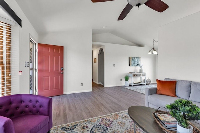 living area featuring lofted ceiling, arched walkways, baseboards, and wood finished floors