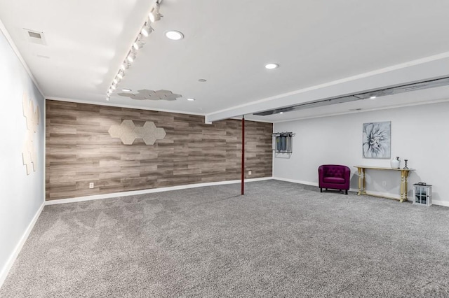 finished basement featuring carpet floors, rail lighting, wooden walls, and an accent wall