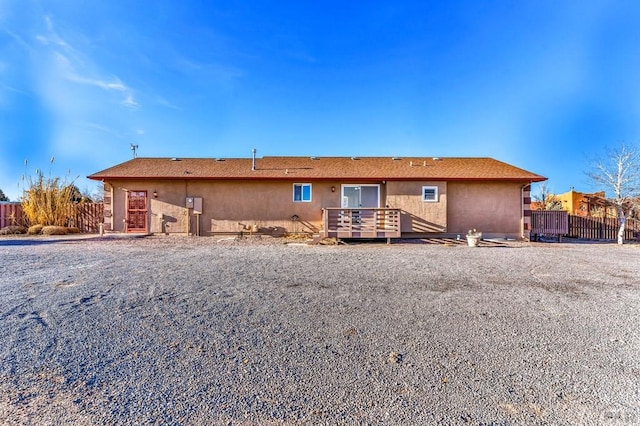 back of property with a deck, fence, and stucco siding