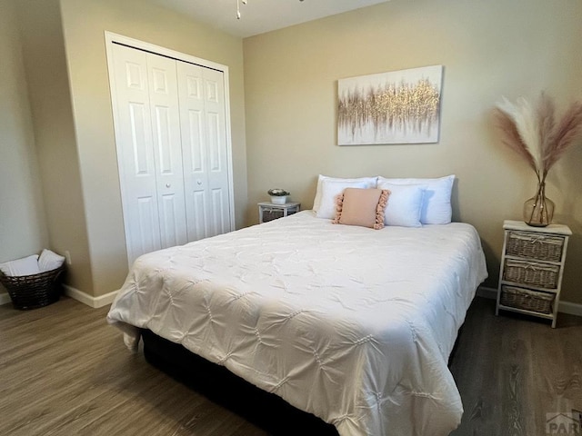 bedroom with dark wood-style flooring, a closet, and baseboards