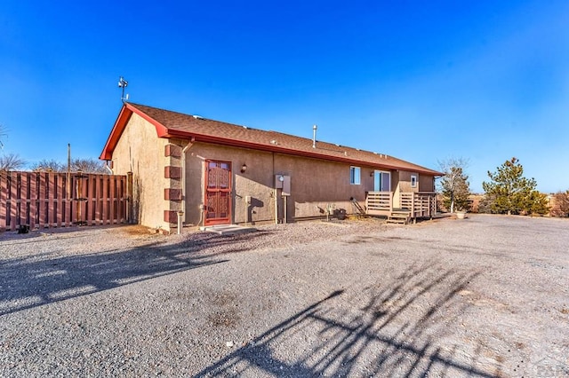 rear view of house featuring fence and stucco siding