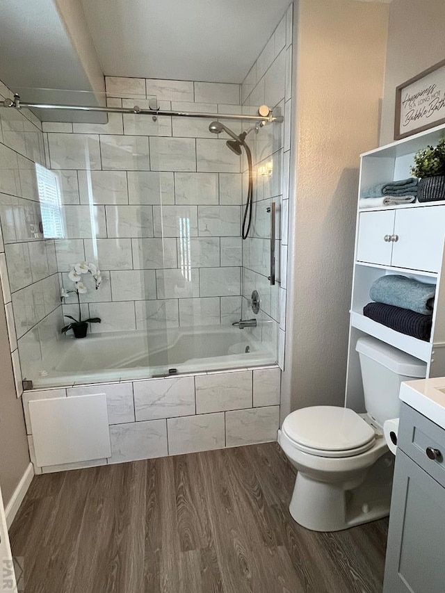 bathroom featuring toilet, tiled shower / bath, wood finished floors, and vanity