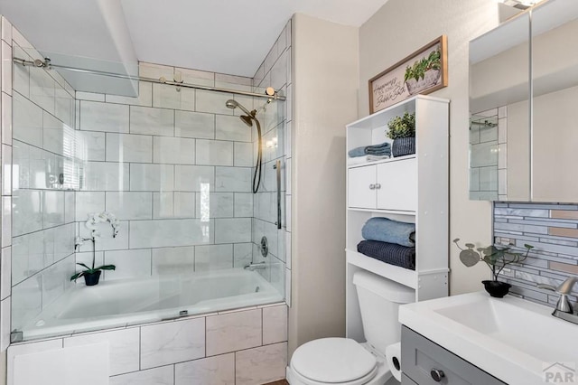 bathroom with tiled shower / bath, vanity, toilet, and decorative backsplash