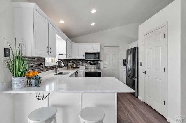 kitchen featuring stainless steel appliances, light countertops, a sink, and a peninsula