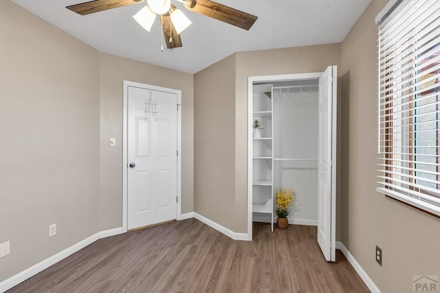 unfurnished bedroom featuring ceiling fan, a closet, wood finished floors, and baseboards