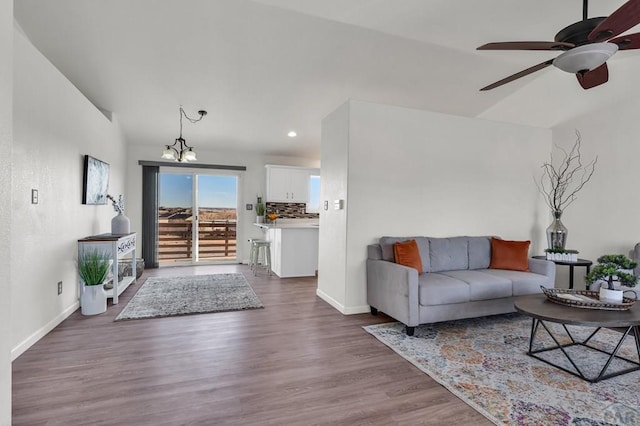 living area with ceiling fan with notable chandelier, recessed lighting, dark wood finished floors, and baseboards