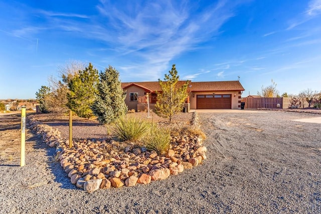 view of front facade featuring an attached garage, fence, and stucco siding