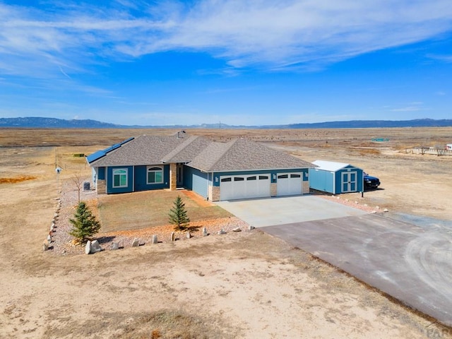 ranch-style home with a storage shed, a mountain view, a garage, an outdoor structure, and driveway