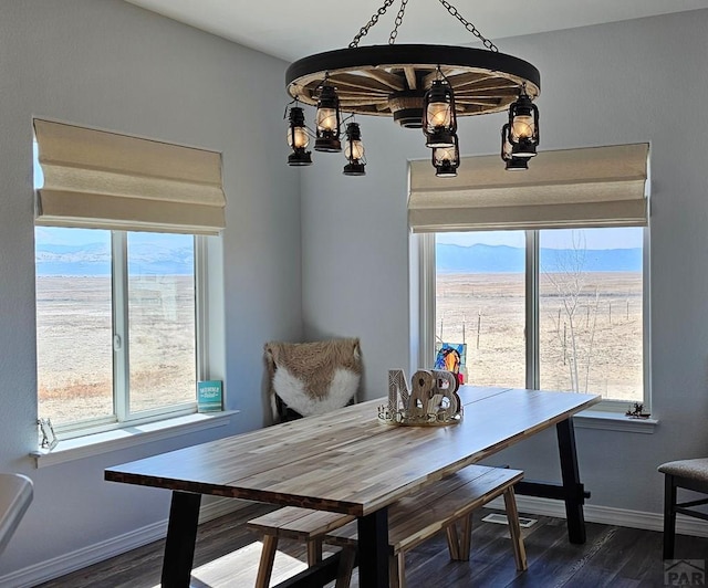 dining room featuring a wealth of natural light, dark wood-style flooring, a mountain view, and baseboards