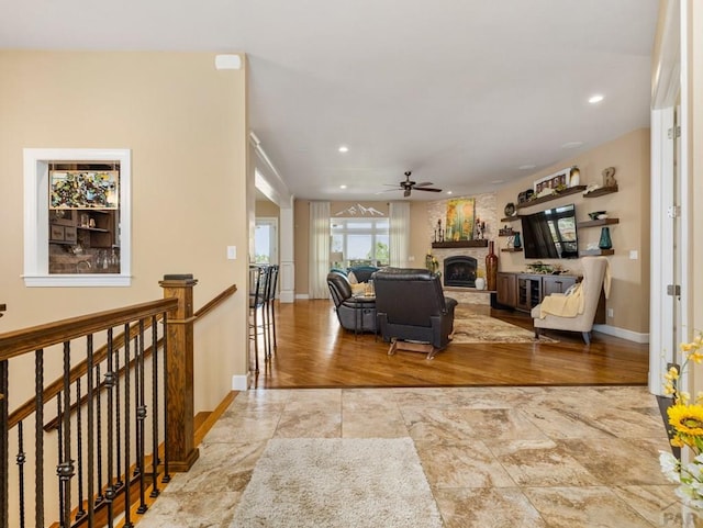 living room featuring a ceiling fan, recessed lighting, a fireplace with raised hearth, and baseboards