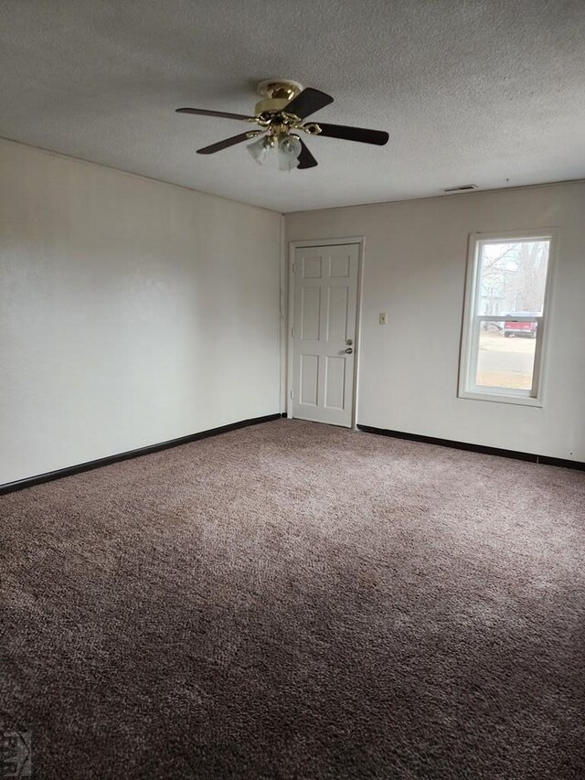 carpeted empty room with a ceiling fan, visible vents, a textured ceiling, and baseboards