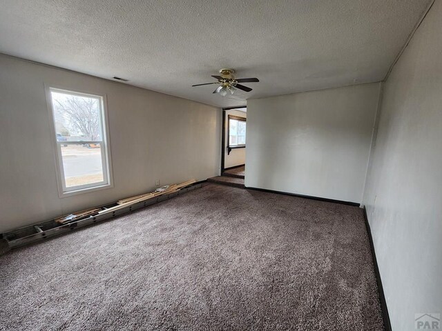 carpeted empty room featuring a ceiling fan, visible vents, and a textured ceiling