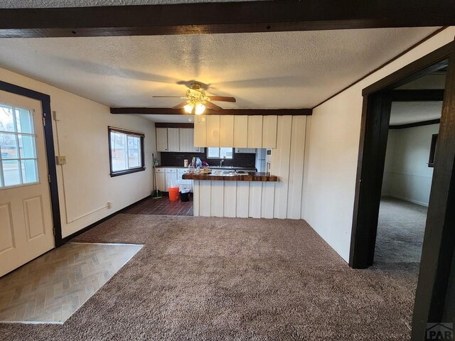 kitchen featuring ceiling fan, butcher block countertops, dark carpet, and a textured ceiling