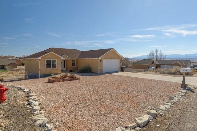 single story home featuring concrete driveway, fence, an attached garage, and a mountain view