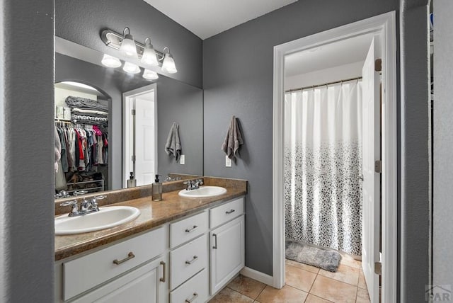 full bathroom with double vanity, curtained shower, tile patterned flooring, and a sink