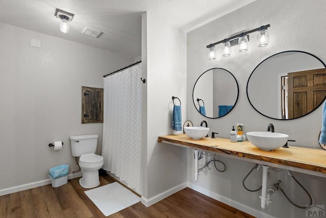 full bath with toilet, baseboards, a sink, and wood finished floors