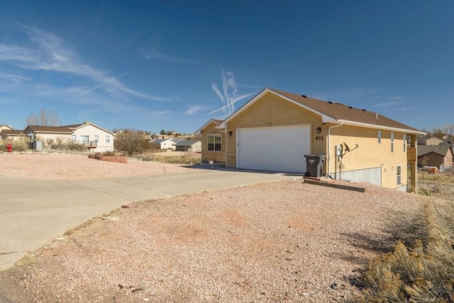 exterior space featuring a residential view, driveway, an attached garage, and stucco siding