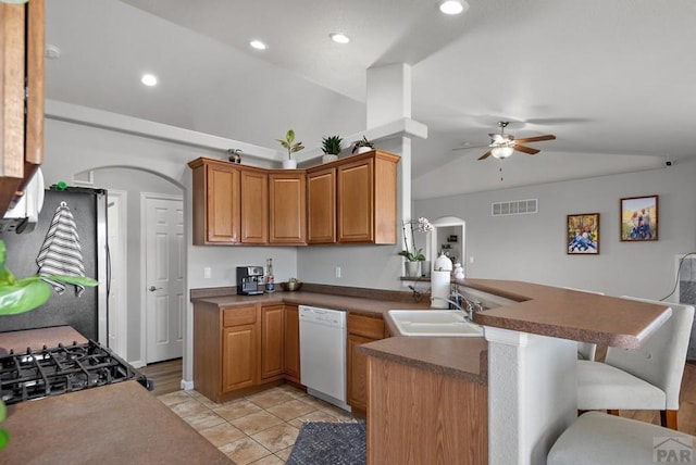 kitchen featuring visible vents, arched walkways, dishwasher, a peninsula, and vaulted ceiling