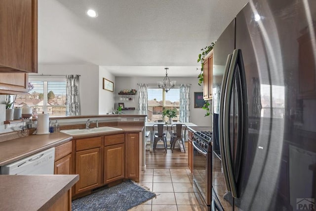 kitchen with white dishwasher, a sink, range with gas stovetop, stainless steel fridge with ice dispenser, and an inviting chandelier