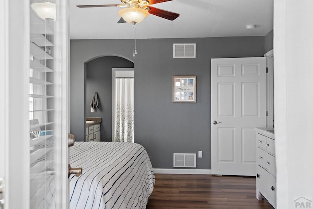 bedroom featuring baseboards, visible vents, arched walkways, and dark wood-type flooring