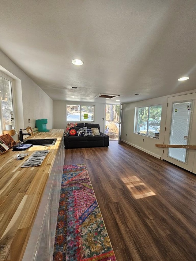 living room featuring baseboards, dark wood finished floors, and a textured ceiling