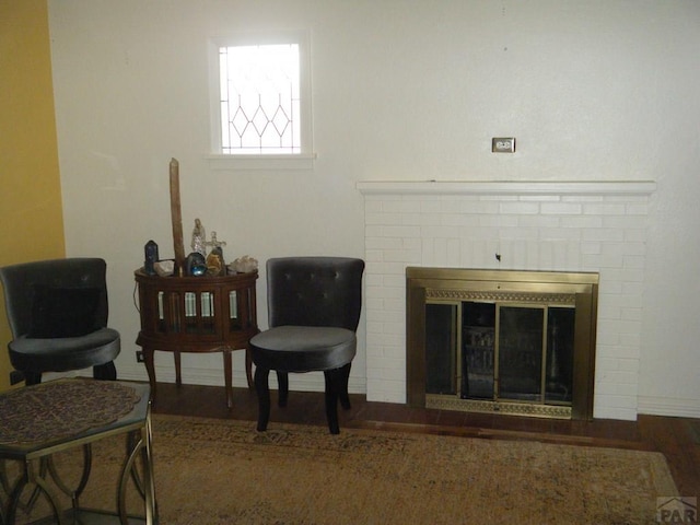 sitting room with a brick fireplace and wood finished floors