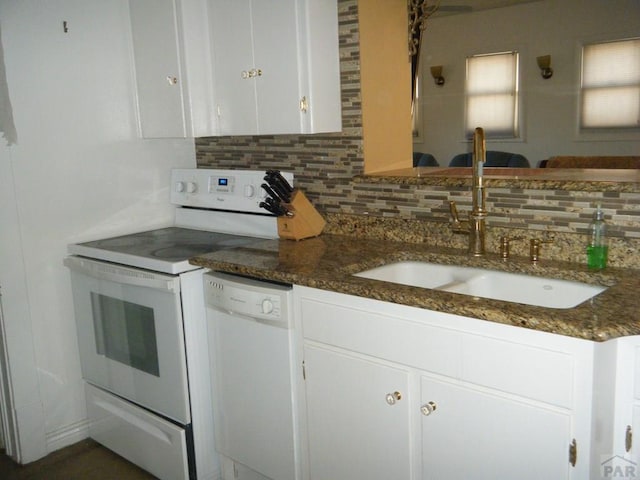 kitchen featuring white appliances, white cabinetry, tasteful backsplash, a sink, and dark stone countertops