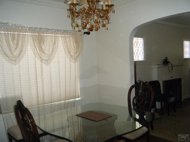 dining space with arched walkways, a notable chandelier, and ornamental molding