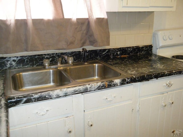 kitchen with decorative backsplash, a sink, white cabinets, and white range