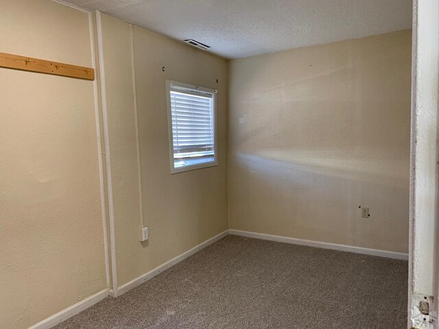 empty room with carpet, a textured ceiling, and baseboards