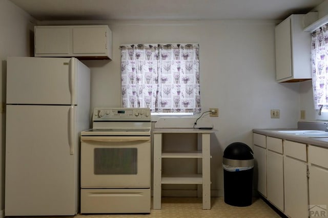 kitchen with light floors, light countertops, white cabinets, a sink, and white appliances