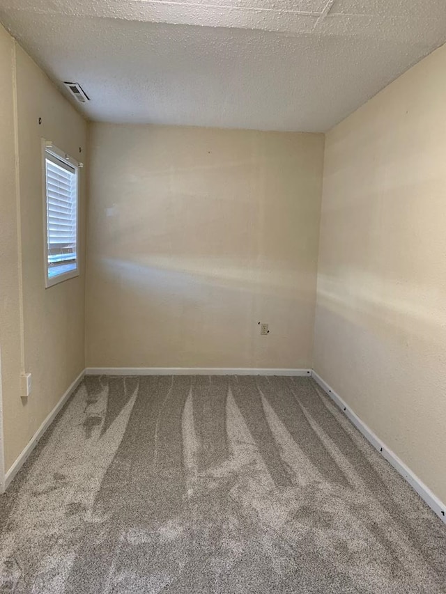 empty room featuring carpet, visible vents, and baseboards