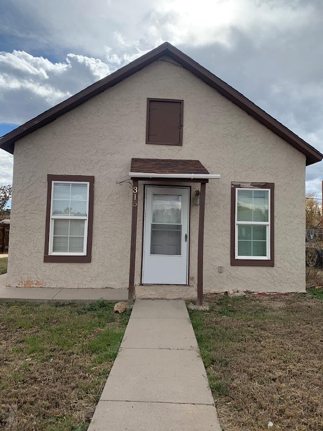 bungalow featuring a front yard and stucco siding