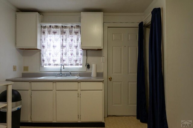 kitchen with light countertops, light floors, a sink, and white cabinets