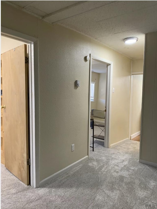 carpeted spare room with a textured wall and baseboards